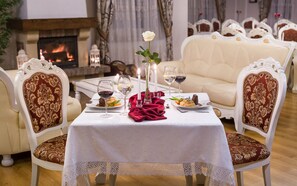 A dining table set for two with a white tablecloth, red napkin, and a vase with a white flower. - Hotel Adam & Spa (Kudowa Zdroj)