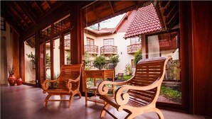 Un espacio al aire libre con techo, con bancos de madera y vistas a un patio con tejado de baldosas y plantas.