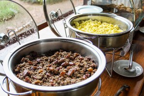 Buffet com diversos pratos, incluindo ovos mexidos, carne moída e outros alimentos já preparados.