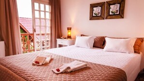 Una habitación de hotel con una cama grande, una mesita de noche con lámpara y vistas a un edificio con tejado rojo.