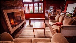 Una sala de estar acogedora con chimenea, asientos cómodos y ventanas grandes.