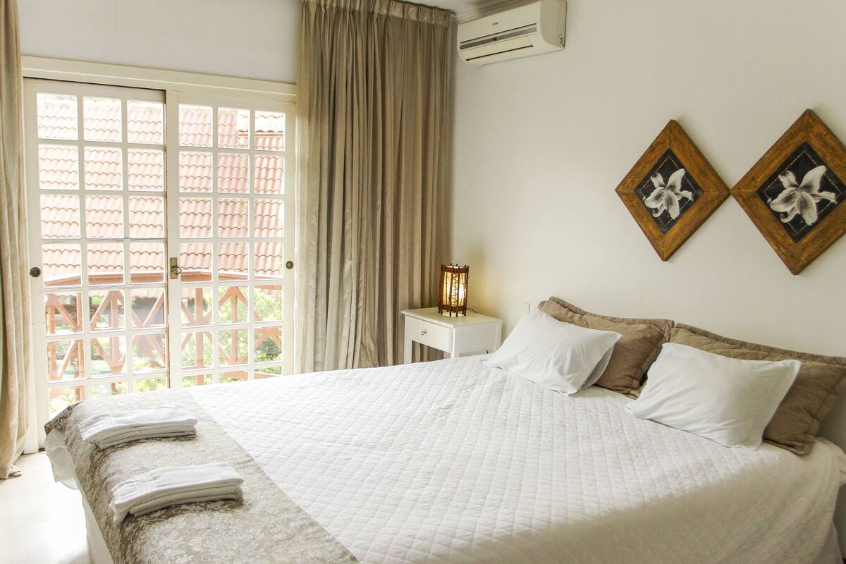 Una habitación de hotel con cama, mesita de noche y ventana con cortinas.