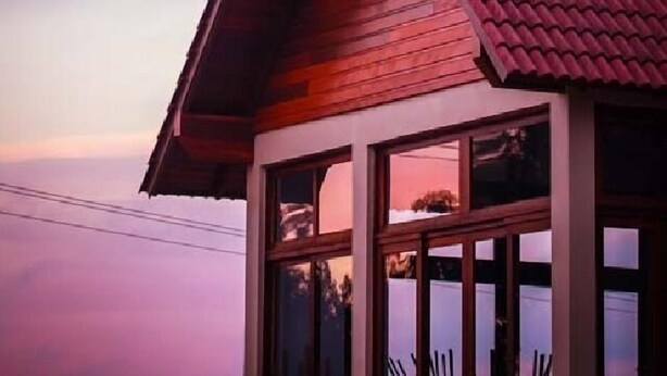Una cabaña de madera con techo de tejas rojas y ventanas amplias.