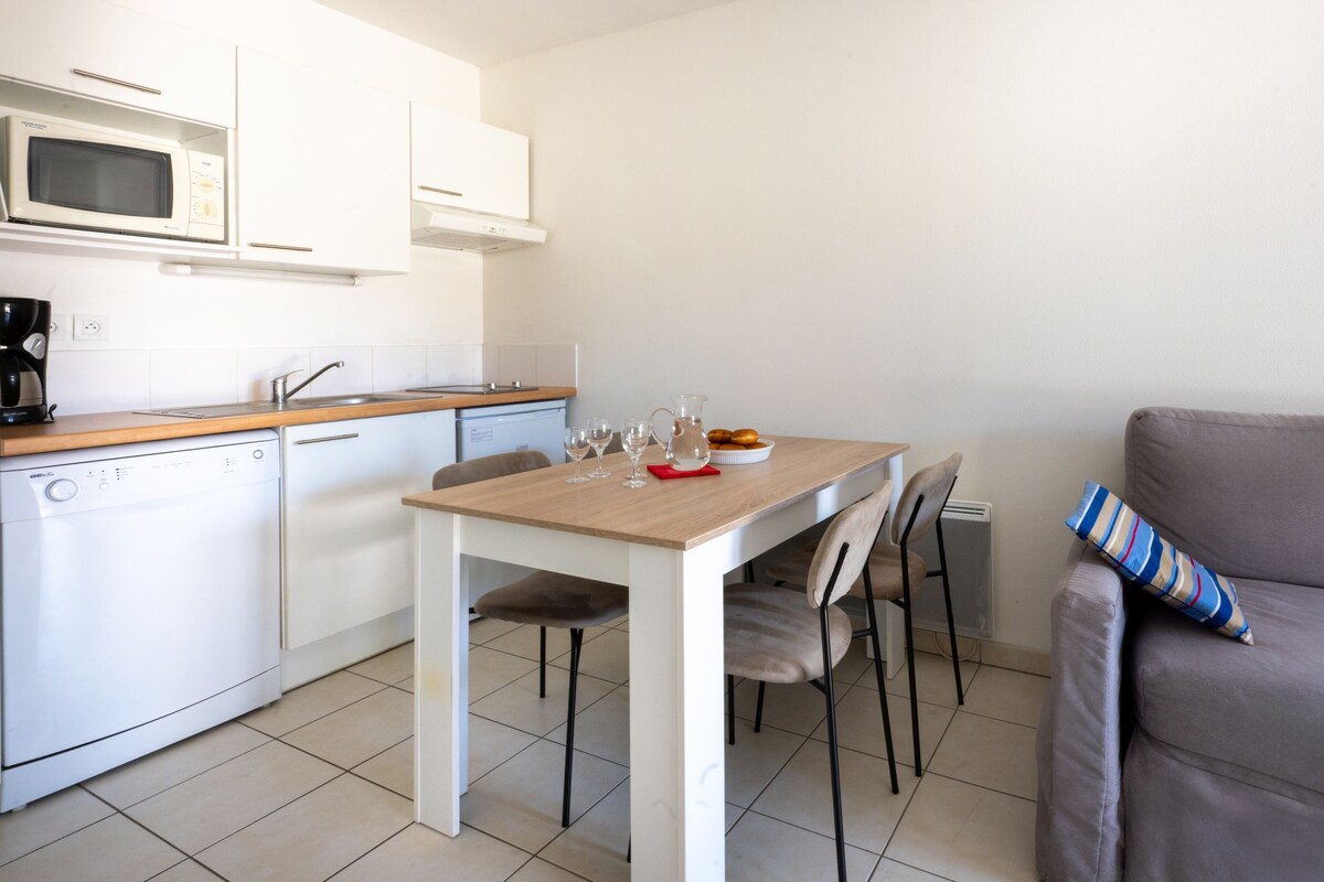 Una cocina compacta con microondas, cafetera y una mesa de comedor con sillas.
