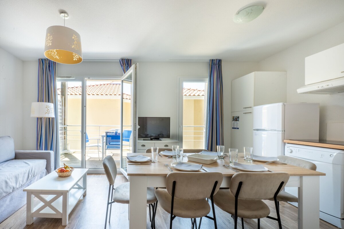Una cocina moderna con comedor, televisor y balcón con vistas.