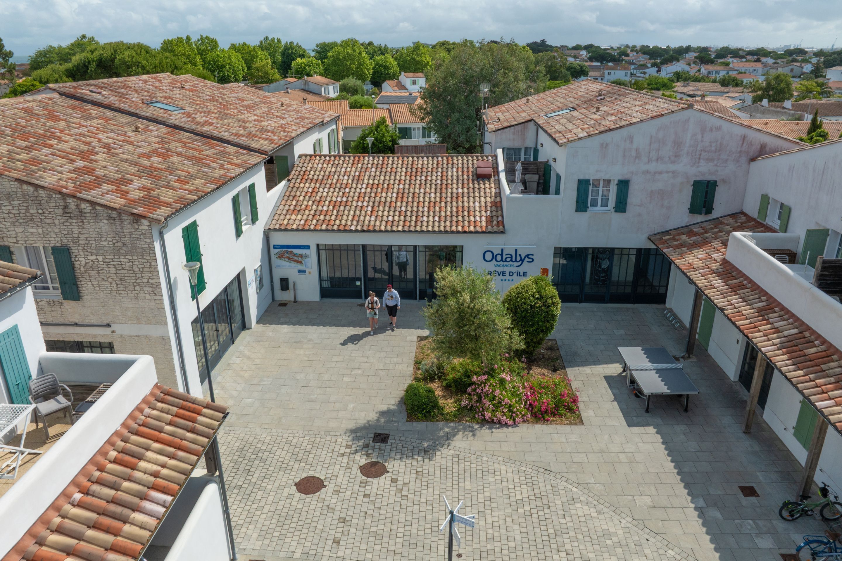 A courtyard with a tiled roof, a small garden, and a sign for 'Odalys Vacances'.