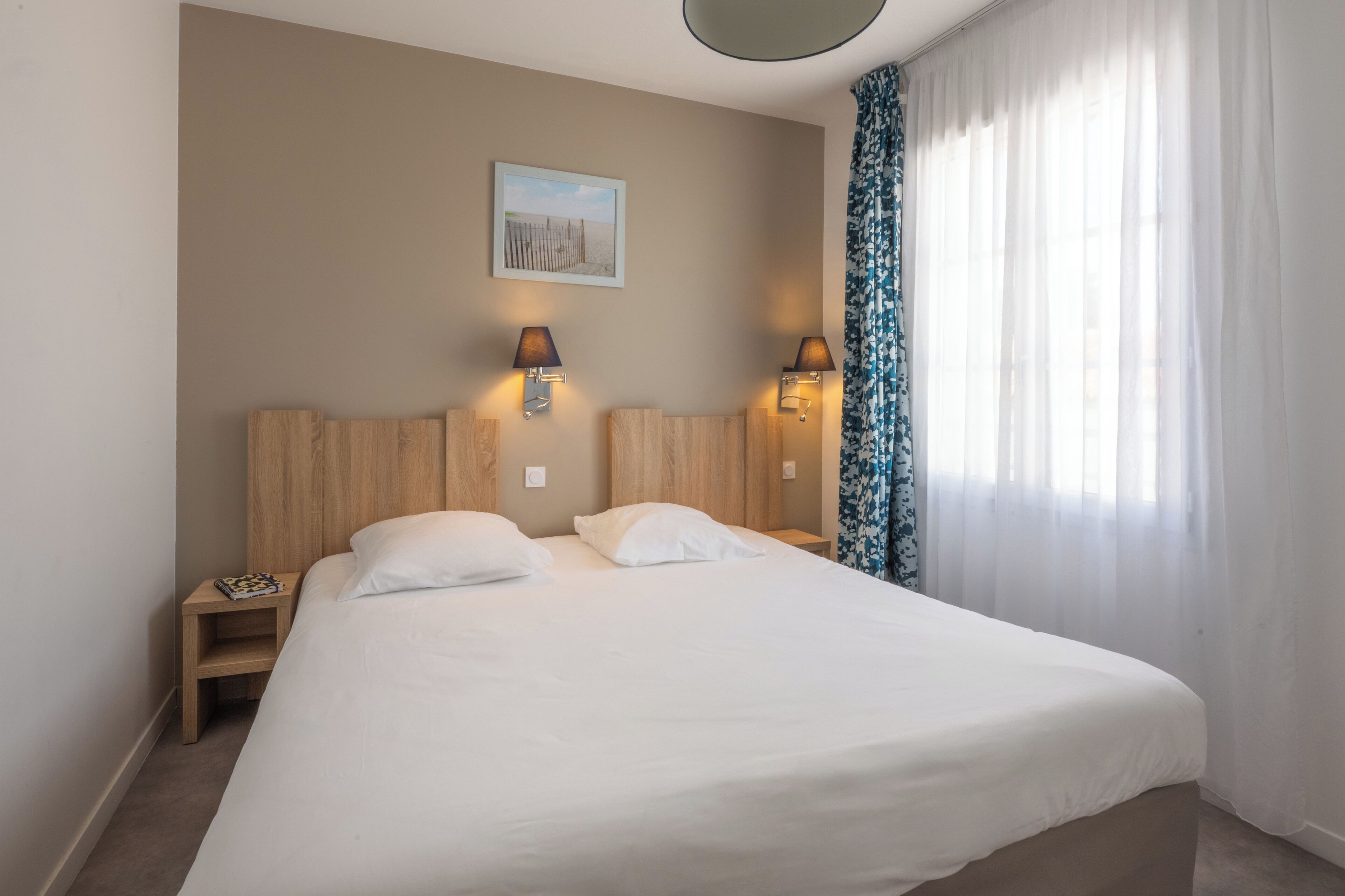 Ein Hotelzimmer mit einem großen Bett, zwei Nachttischen und einem an der Wand hängenden Bild.