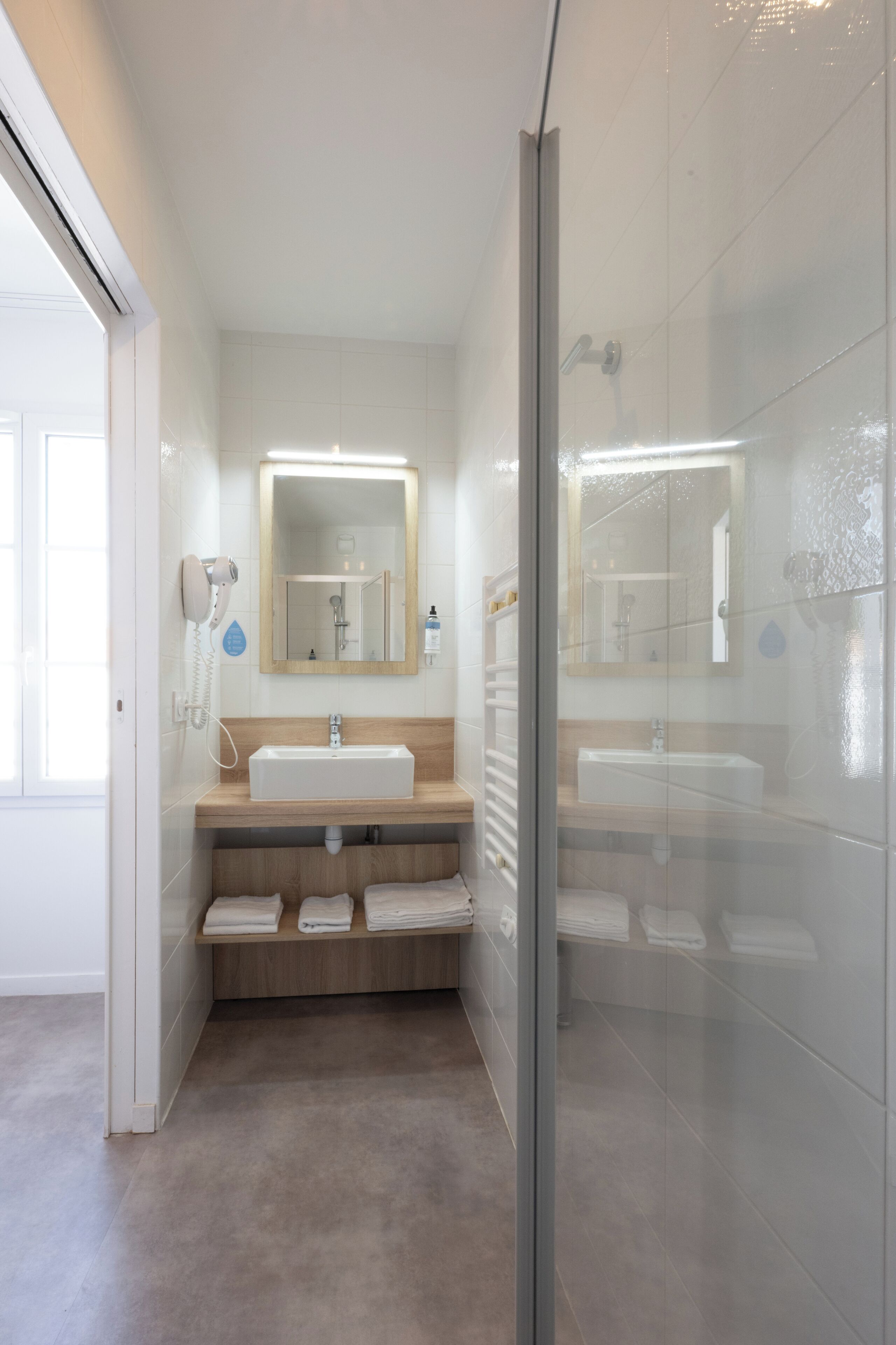 Een moderne badkamer met een douchecabine van glas, een grote spiegel en een wastafelmeubel met wastafel en handdoekrek.