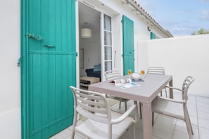 Un coin repas avec une table et des chaises, une fenêtre avec des rideaux et une porte dotée d’un loquet.
