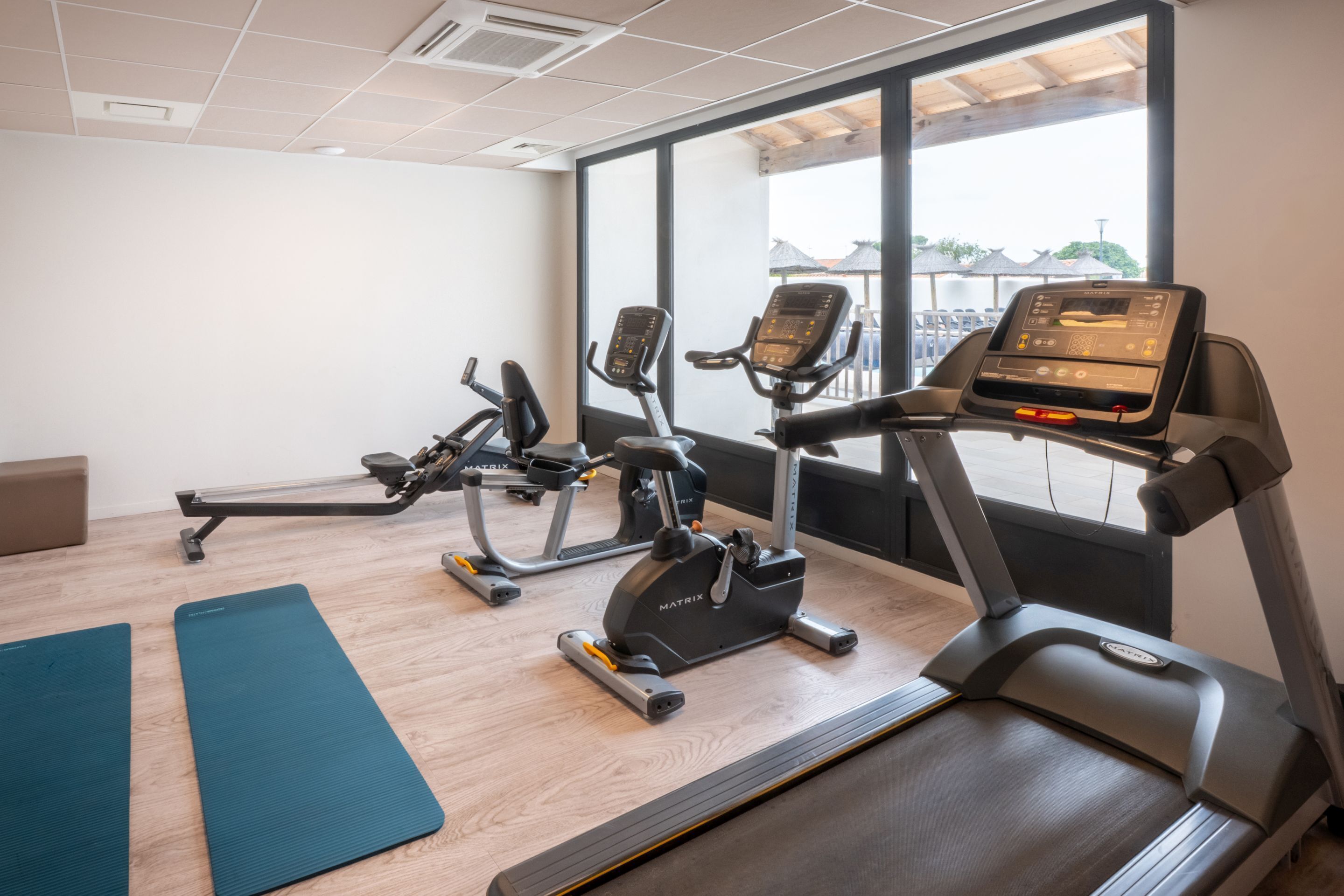 A gym with treadmills, elliptical machines, and exercise mats.
