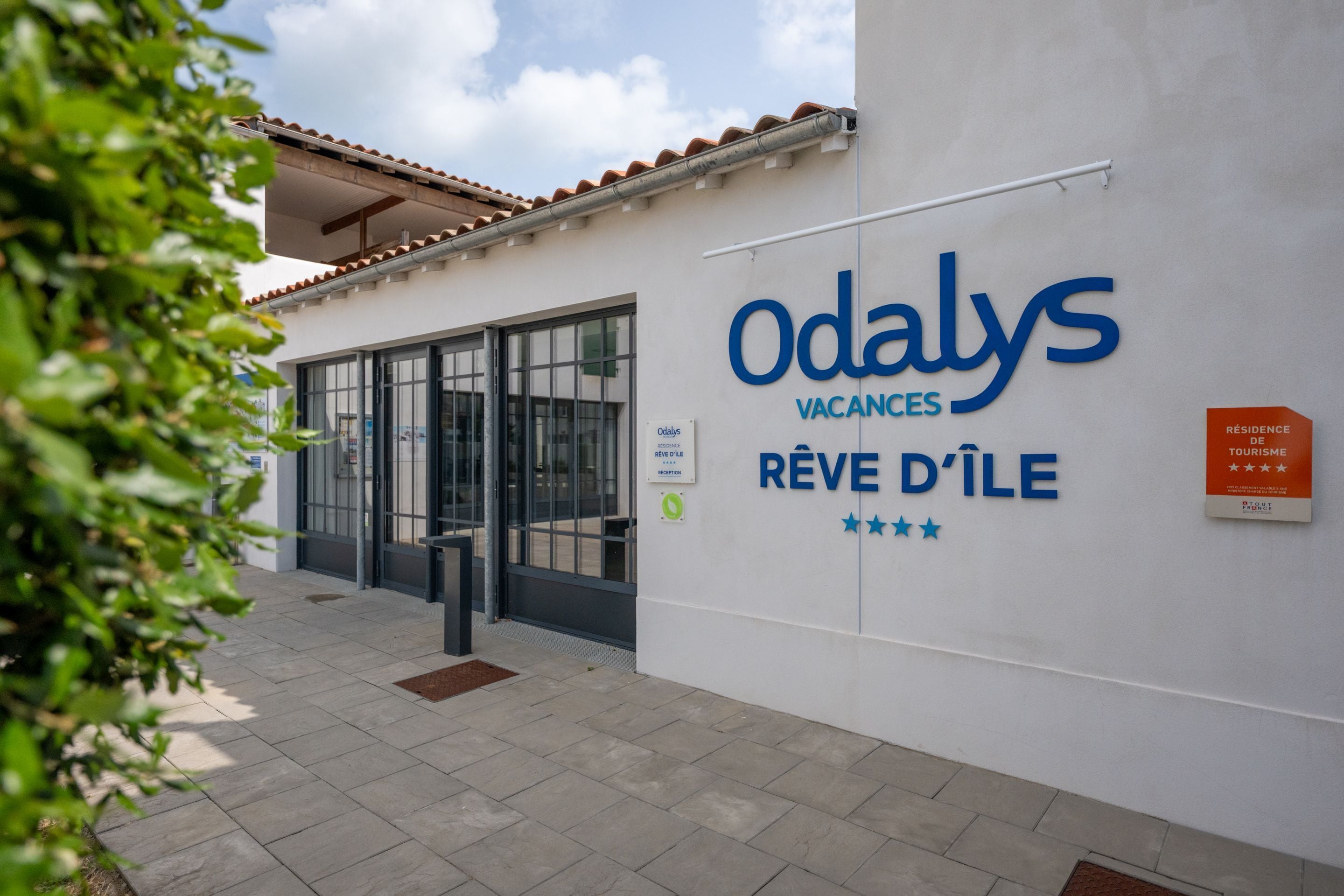 A building with a sign reading "Odaly's Vacances Rêve d'Île" and a reception desk.
