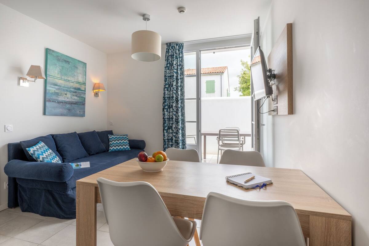Ein modernes Wohnzimmer mit einer Couch, einem Esstisch, Stühlen und einer Obstschale.