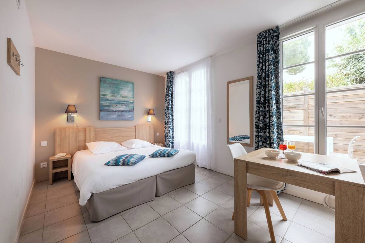 Ein Schlafzimmer mit Bett, Nachttischen, einem Schreibtisch und einem Stuhl.