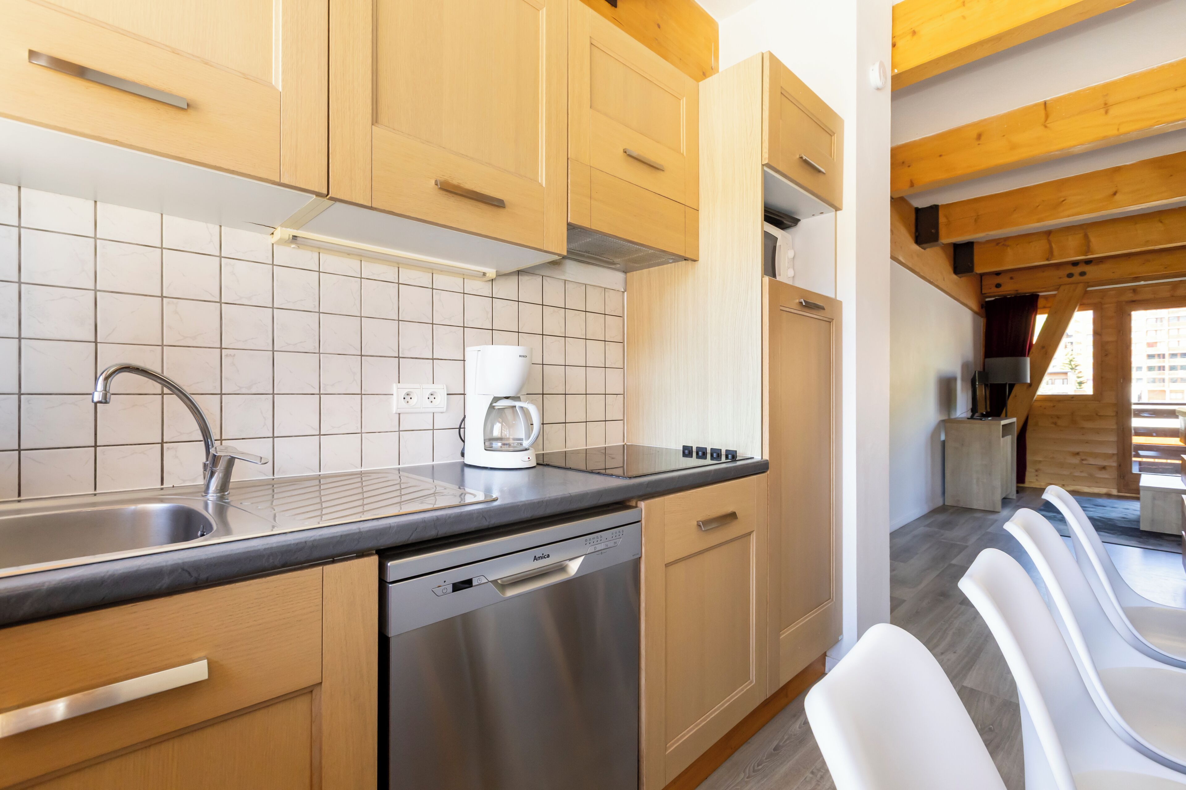 A modern kitchen with wooden cabinets, a stainless steel dishwasher, and a coffee maker.