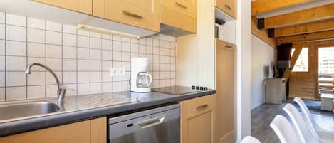 A modern kitchen with wooden cabinets, a stainless steel dishwasher, and a coffee maker.
