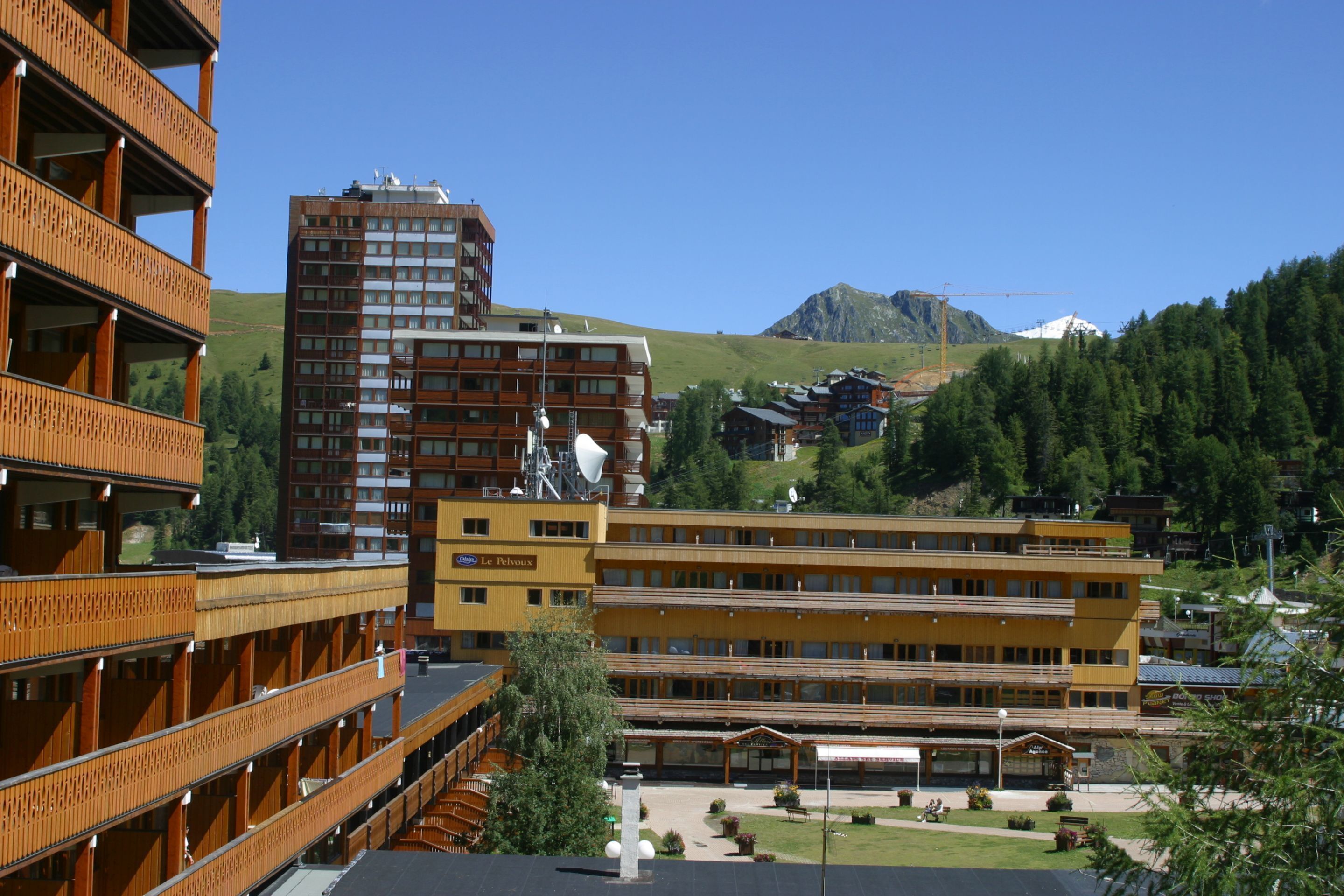 Ein Hotel mit mehreren Etagen, Balkonen und einer Bergkulisse.