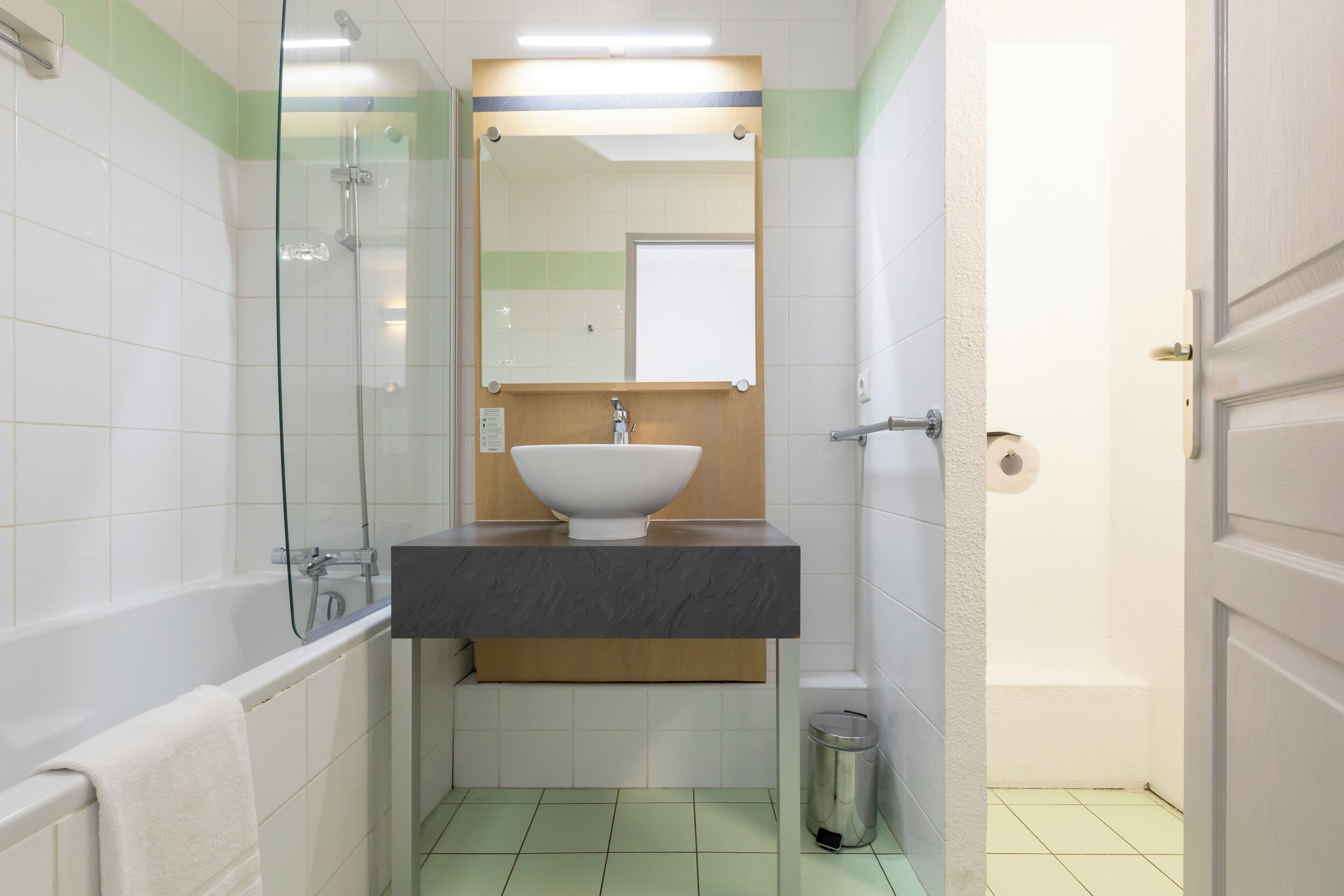 Ein Badezimmer mit einer Badewanne, einem Waschbecken mit Spiegel darüber und einem Mülleimer.