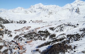 A snow-covered mountain village with buildings and ski slopes.