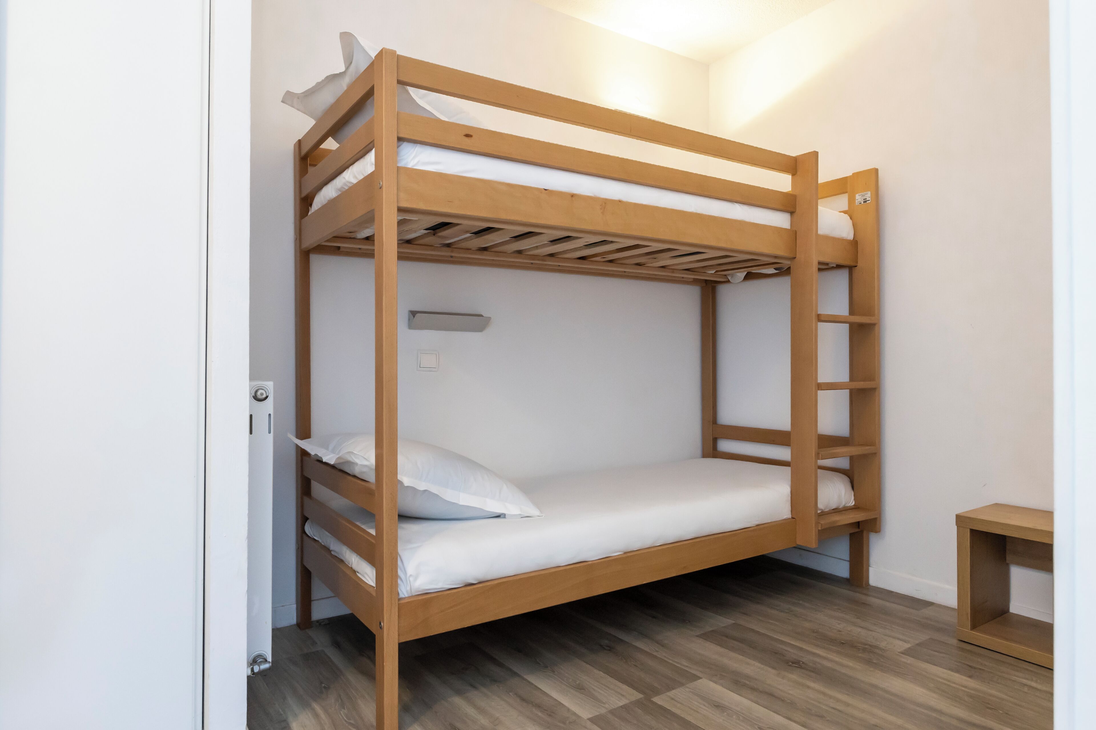 Ein Stockbett mit einer Leiter, ein Nachttisch und eine Wandleuchte.