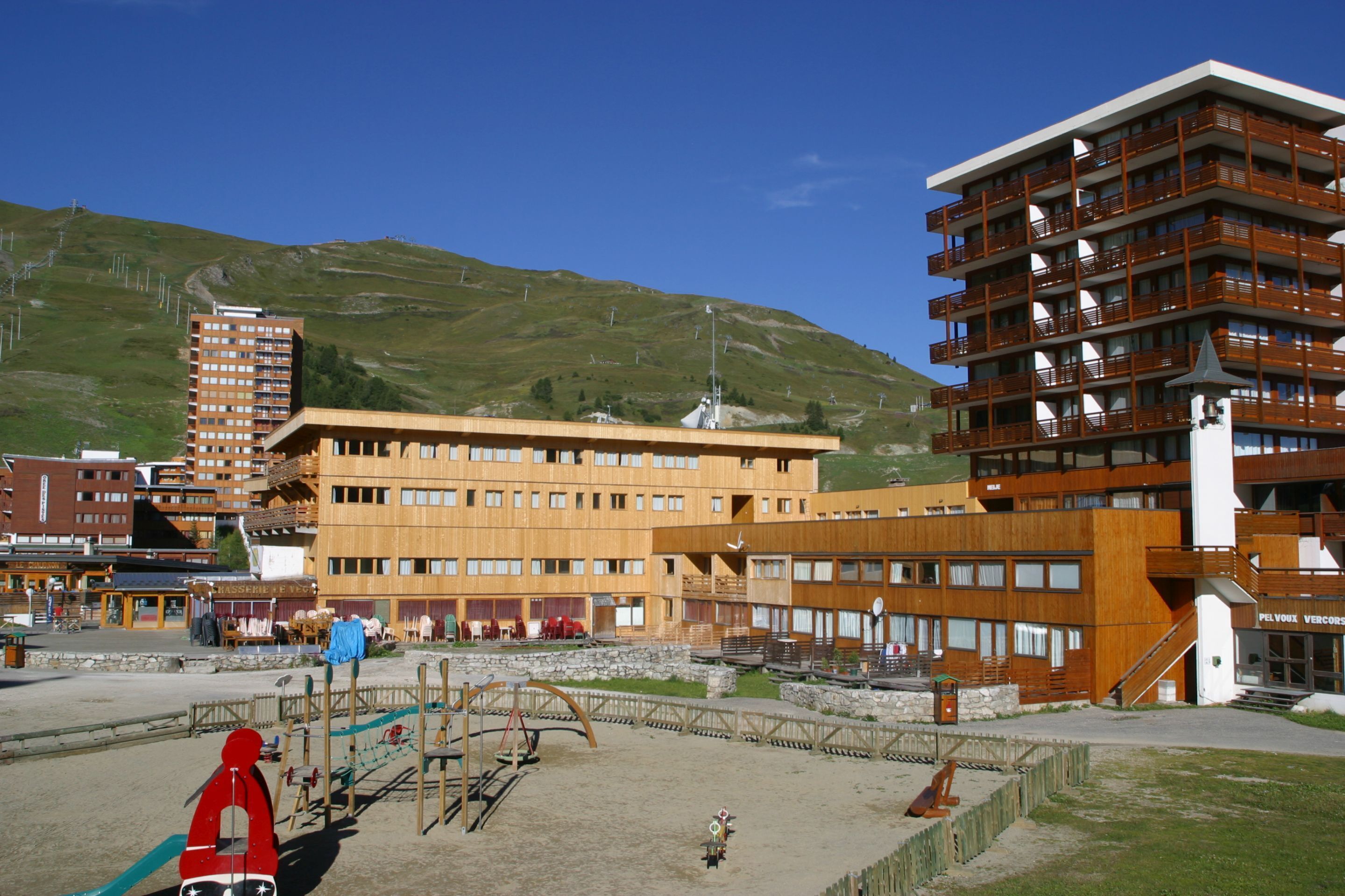 A modern hotel with multiple floors, a central courtyard, and a view of a mountainous landscape.