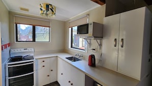 Une cuisine avec des meubles blancs, une cuisinière, un four à micro-ondes et un évier.