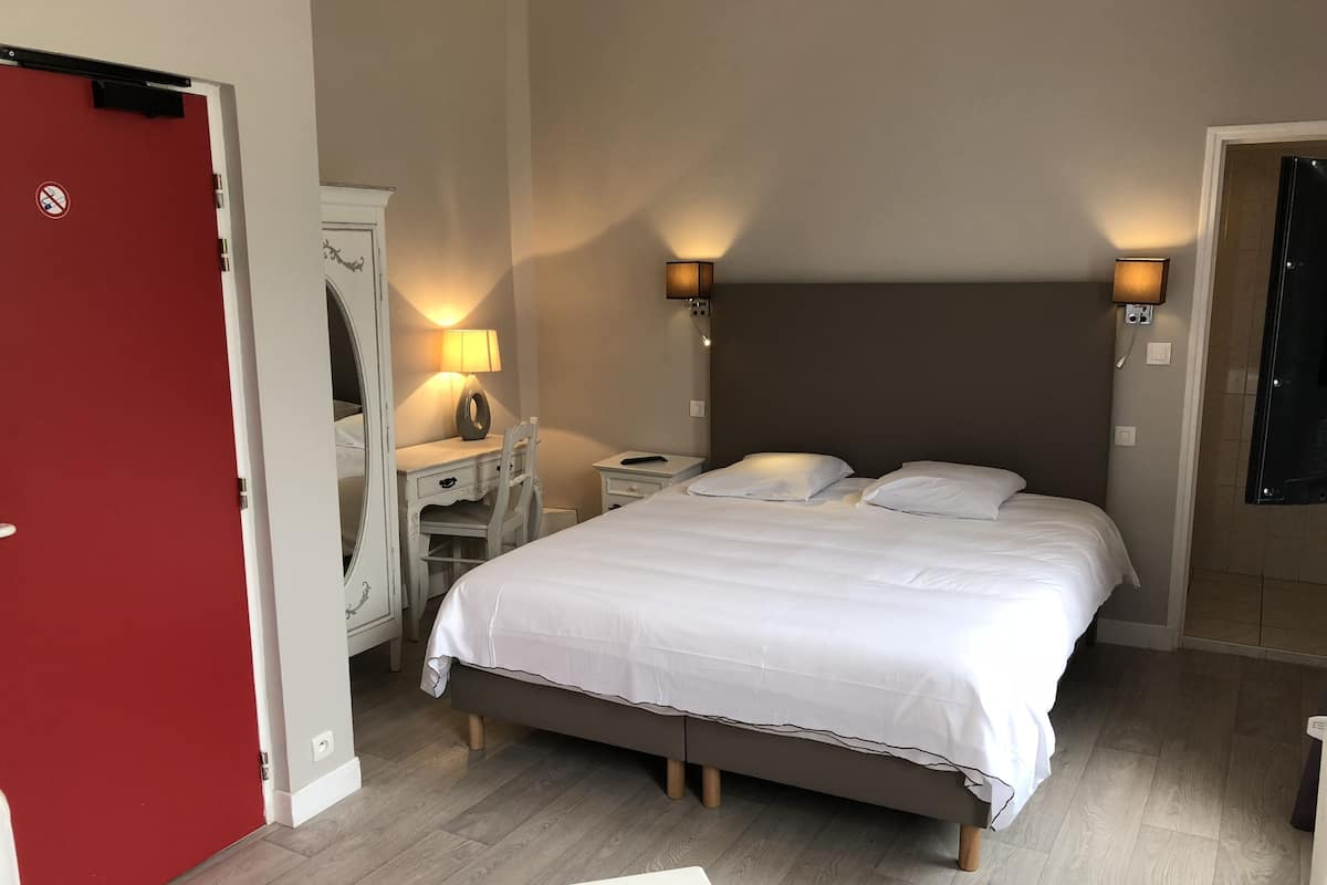 A bedroom with a bed, bedside lamps, a dresser, and a mirror.
