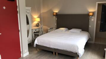 A bedroom with a bed, bedside lamps, a dresser, and a mirror.