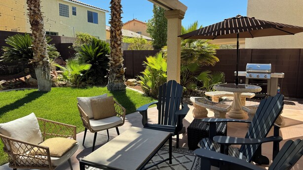 An outdoor patio area with a grill, chairs, and a table. - Best Kept Secret! 4 King Beds ·Hot Tub · 9ft Pool Table · 5 Min to South Point (Las Vegas)