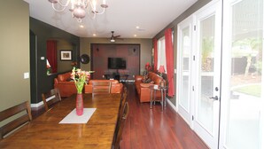 A spacious living room with a dining area, a chandelier, a flat-screen TV, and a sliding glass door to the outdoors. - Best Kept Secret! 4 King Beds ·Hot Tub · 9ft Pool Table · 5 Min to South Point (Las Vegas)