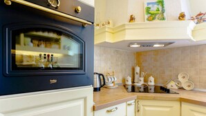 A kitchen with a built-in oven, white cabinets, and a countertop with various kitchen items.