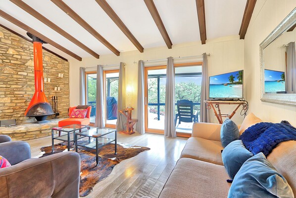 Un salón espacioso con pared de piedra, chimenea, sofá y televisor.