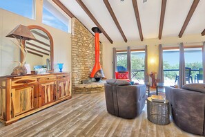 A spacious living area with a stone wall, a red chimney, and a wooden cabinet.