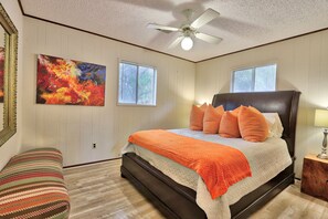 A bedroom with a large bed, two windows, a ceiling fan, and a painting on the wall. - Close to town - Amazing Views - Pet Friendly house in Wimberley! (Wimberley)
