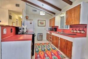 A compact kitchen with wooden cabinets, a refrigerator, a microwave, and a sink.