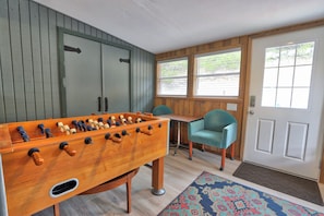 A room with a foosball table, a desk, a teal chair, and a door with a window. - Close to town - Amazing Views - Pet Friendly house in Wimberley! (Wimberley)