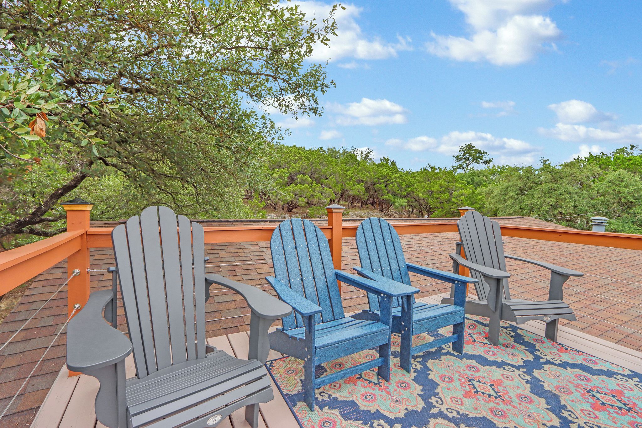 Um deck com cadeiras Adirondack e um tapete estampado.