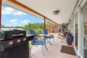 A covered outdoor area with a barbecue grill, seating, and a view of the surrounding greenery. - Close to town - Amazing Views - Pet Friendly house in Wimberley! (Wimberley)