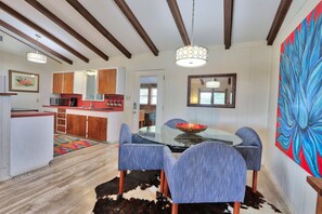 A modern kitchen with wooden cabinets, a microwave, and a dining area with a glass table and blue chairs. - Close to town - Amazing Views - Pet Friendly house in Wimberley! (Wimberley)