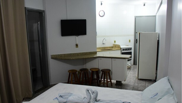 A compact hotel room with a bed, a small kitchenette, a TV, and a bathroom. - ADTUR CTC Condomínio Golden (Caldas Novas)