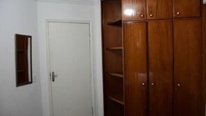 A white door with a small mirror and a wooden wardrobe with multiple shelves. - ADTUR CTC Condomínio Golden (Caldas Novas)