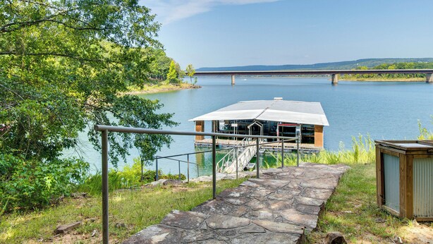 A stone pathway leading to a dock with a covered boat house, a metal railing, and a small shed by the water. - Greers Ferry Lakefront Home w/ Deck & Boat Slips! (Greers Ferry)