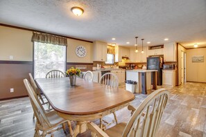 Une cuisine spacieuse avec un coin repas, des meubles de cuisine en bois et une horloge au mur.