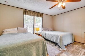 Une chambre avec deux lits, un ventilateur de plafond et une fenêtre avec des rideaux.