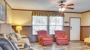 A living room with a sofa, two armchairs, a ceiling fan, and a door. - Greers Ferry Lakefront Home w/ Deck & Boat Slips! (Greers Ferry)