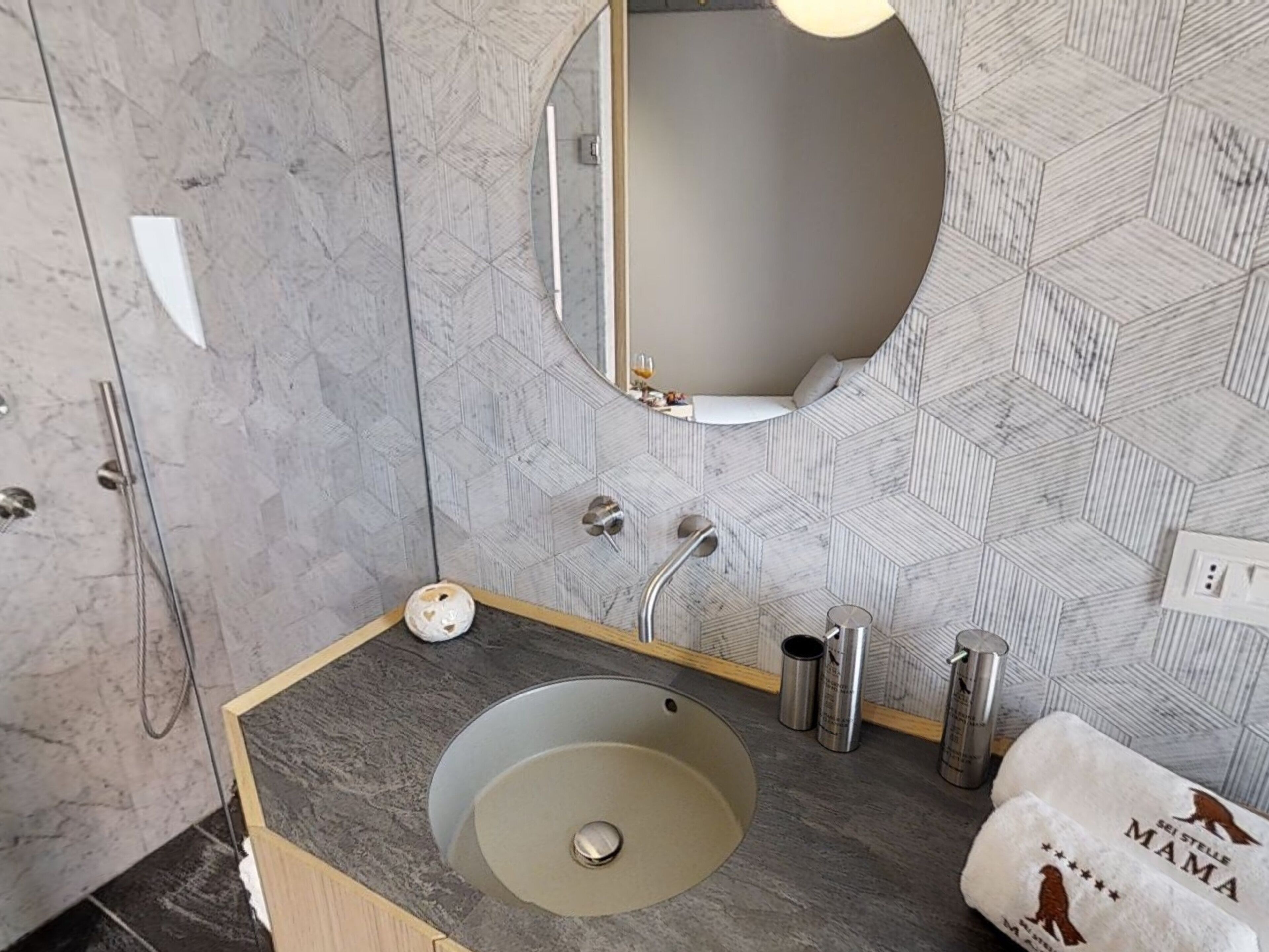 Un baño con lavamanos de mármol, un espejo y una toalla con la palabra 'MAMA'.