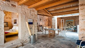 A rustic stone interior with a wooden ceiling, a bed, a table with chairs, and a painting on the wall. - Exclusive villa with private pool in Ragusa, DiCasaInSicilia (Santa Croce Camerina)