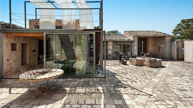 A modern glass structure with a stone exterior, a scooter, and a stone table in a courtyard. - Exclusive villa with private pool in Ragusa, DiCasaInSicilia (Santa Croce Camerina)