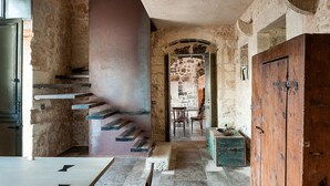 A stone-walled interior with a staircase, wooden door, and a table with chairs. - Exclusive villa with private pool in Ragusa, DiCasaInSicilia (Santa Croce Camerina)