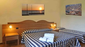 Une chambre d’hôtel avec deux lits, une tête de lit en bois, une table de chevet et un tableau représentant un paysage urbain.