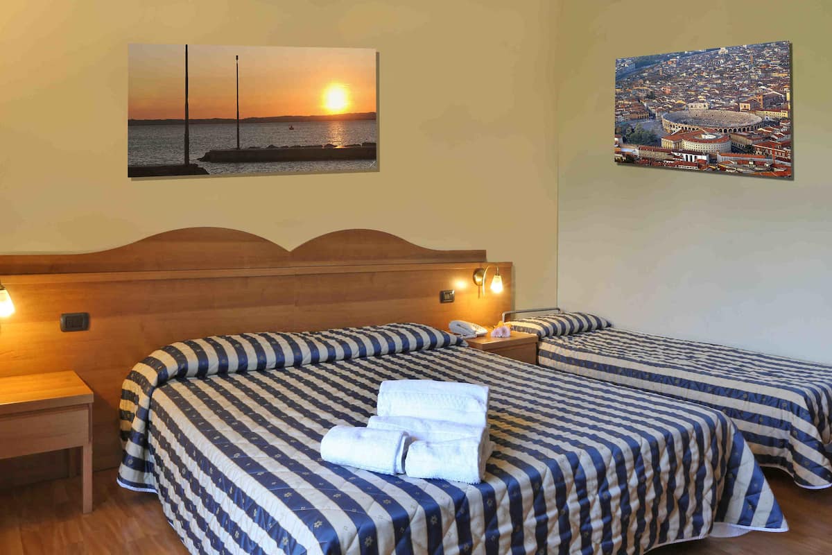 Ein Hotelzimmer mit zwei Betten, einem Holzkopfende, einem Nachttisch und einem Stadtbild.